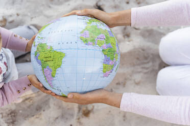 Hands of mother and little daughter holding Earth beach ball, close-up - DIGF08837