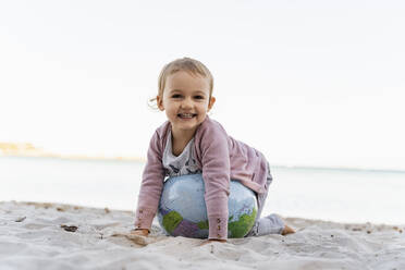Porträt eines glücklichen kleinen Mädchens, das mit einem Strandball aus Erde spielt - DIGF08849