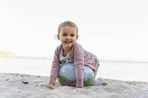 Portrait of happy little girl playing with Earth beach ball - DIGF08849