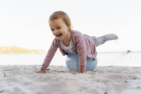 Porträt eines lachenden kleinen Mädchens, das auf einem Strandball aus Erde balanciert, lizenzfreies Stockfoto