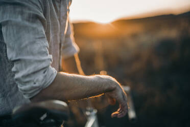 Nahaufnahme eines jungen Mannes mit seinem Rennrad im Sonnenschein - MKF00010