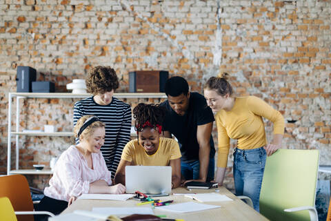 Young people working together at table using laptop stock photo