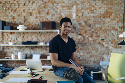 Portrait of confident young man at table in office - SODF00124