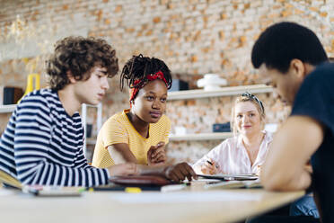 Young people sitting together at table and talking - SODF00133