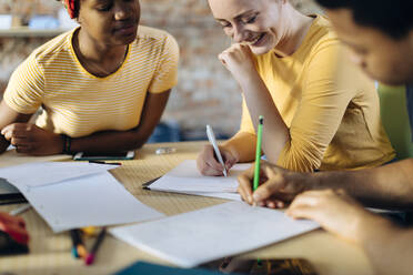 Young people sitting together at table and taking notes - SODF00144