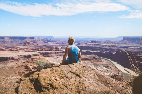 Rear view of man looking at rocky mountains against sky - CAVF68202