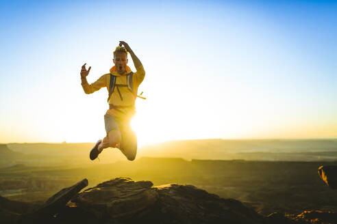 Aufgeregter Wanderer beim Sprung auf einen Berg im Canyonlands National Park - CAVF68205