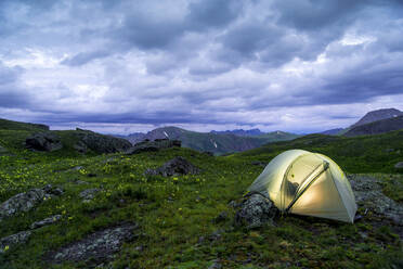 Illuminated tent on field against stormy clouds at San Juan National Forest - CAVF68218