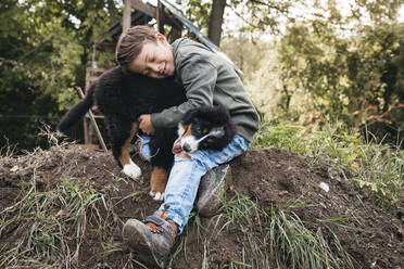 Boy playing with his Bernese mountain dog in the garden - HMEF00667