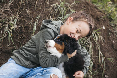 Junge spielt mit seinem Berner Sennenhund im Garten - HMEF00669