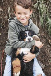 Junge spielt mit seinem Berner Sennenhund im Garten - HMEF00670