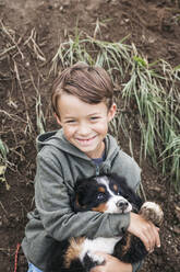 Junge spielt mit seinem Berner Sennenhund im Garten - HMEF00671