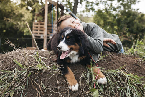 Boy playing with his Bernese mountain dog in the garden - HMEF00673