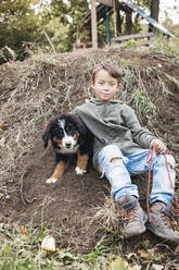 Boy playing with his Bernese mountain dog in the garden - HMEF00674