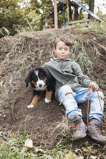 Junge spielt mit seinem Berner Sennenhund im Garten - HMEF00674