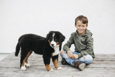 Boy playing with his Bernese mountain dog in the garden - HMEF00675