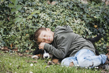 Boy playing with his Bernese mountain dog in the garden - HMEF00676