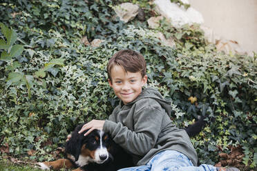 Boy playing with his Bernese mountain dog in the garden - HMEF00677