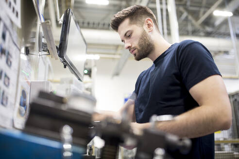 Ein Mann arbeitet in einer modernen Fabrik und bedient eine Maschine - WESTF24245