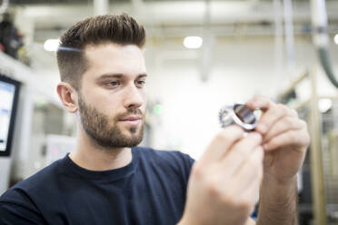 Ein Mann prüft ein Werkstück in einer Fabrik - WESTF24253