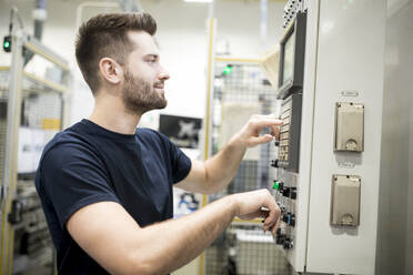 Ein Mann arbeitet in einer modernen Fabrik und bedient eine Maschine - WESTF24254