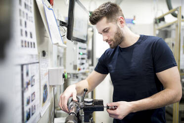 Ein Mann arbeitet in einer modernen Fabrik und bedient eine Maschine - WESTF24256