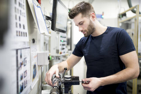 Ein Mann arbeitet in einer modernen Fabrik und bedient eine Maschine - WESTF24256