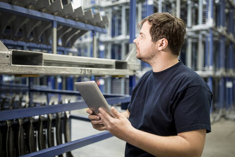 Arbeiter mit Tablet in einem Fabriklager, lizenzfreies Stockfoto