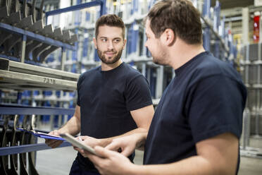 Two workers with clipboard and tablet in factory warehouse - WESTF24275