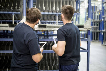 Two workers with clipboard and tablet in factory warehouse - WESTF24277