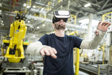 Man wearing VR glasses in modern factory - WESTF24308