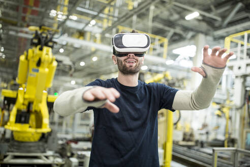 Man wearing VR glasses in modern factory - WESTF24309