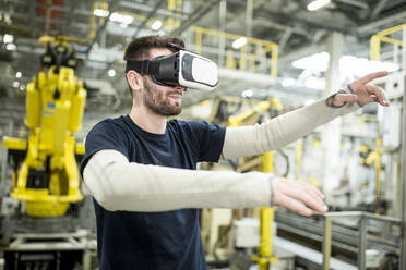 Man wearing VR glasses in modern factory - WESTF24310