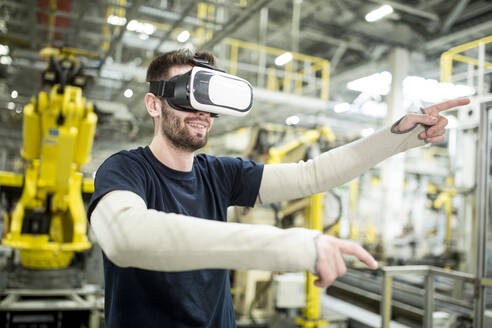 Man wearing VR glasses in modern factory - WESTF24311