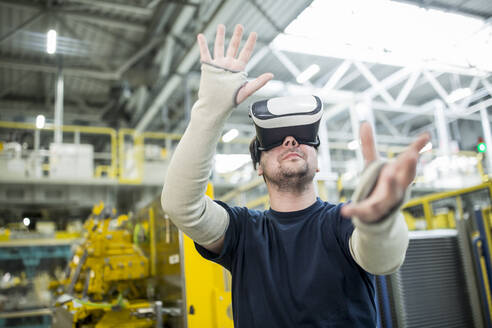 Man wearing VR glasses in modern factory - WESTF24318