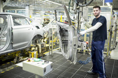 Porträt eines selbstbewussten Arbeiters in einer modernen Autofabrik, lizenzfreies Stockfoto