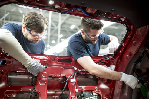 Two colleagues working at bodywork in modern car factory - WESTF24359