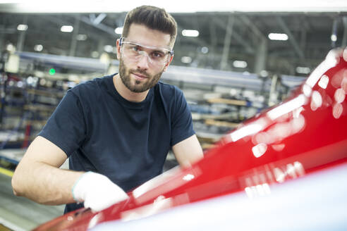 Porträt eines selbstbewussten Mannes, der in einer modernen Autofabrik arbeitet - WESTF24362