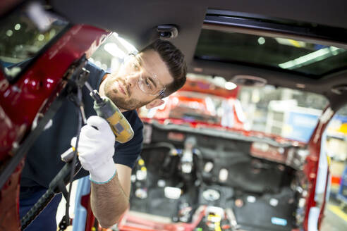 Man working at bodywork in modern car factory - WESTF24364