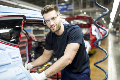 Porträt eines selbstbewussten Mannes, der in einer modernen Autofabrik arbeitet - WESTF24368