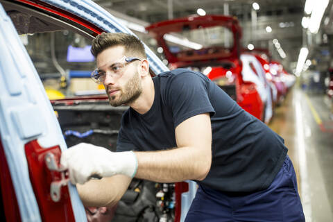 Mann arbeitet in einer modernen Autofabrik, lizenzfreies Stockfoto