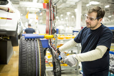 Man working on tyre in modern car factory - WESTF24383