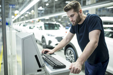 Mann arbeitet am Computer in einer modernen Autofabrik - WESTF24416