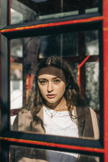 Young woman in a telephone box, looking at camera - MKF00018