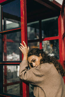 Young woman leaning on a telephone box - MKF00019