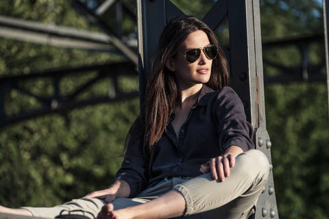 Young woman enjoying the evening sun, sitting on a bridge stock photo