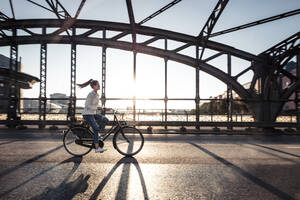 Junger Radfahrer auf einer Brücke bei Sonnenuntergang - WFF00143