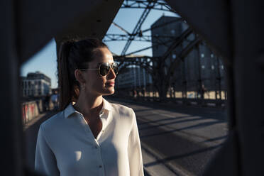 Junge Frau auf einer Brücke im Abendlicht, gesehen durch den Brückenpfeiler - WFF00145