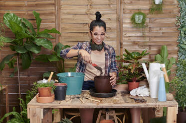 Smiling young woman gardening on her terrace - IGGF01385