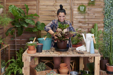 Smiling young woman gardening on her terrace - IGGF01386